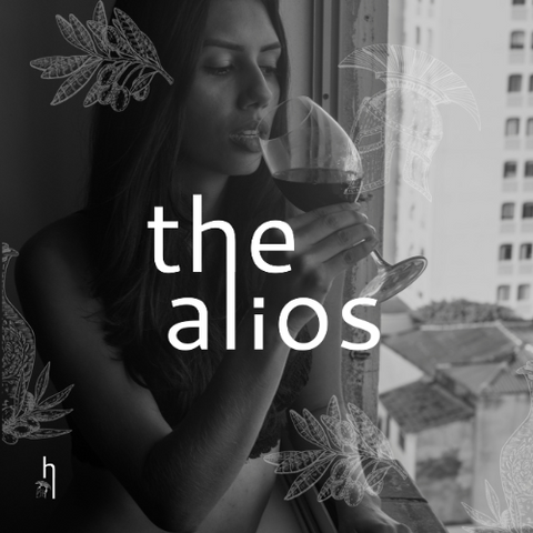 a black and white photo of a woman holding a glass of wine with the words the alios above her