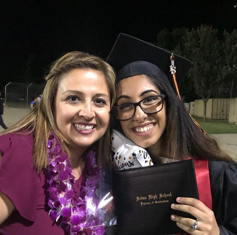 The author in graduation regalia posing with her teacher