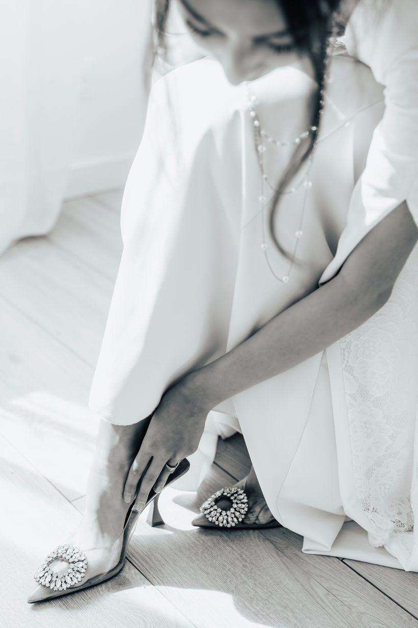 Lors des préparatifs, la mariée, déjà en robe, enfile ses chaussures. Noir et blanc. Photographe de mariage Provence et Côte d'Azur