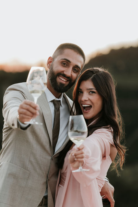 Un couple enlacé lève leurs coupe de champagne vers le photographe en riant - photographe de mariage Italie, Monaco et Côte d'Azur
