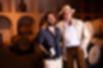 Two men smiling in a wine cellar with barrels.
