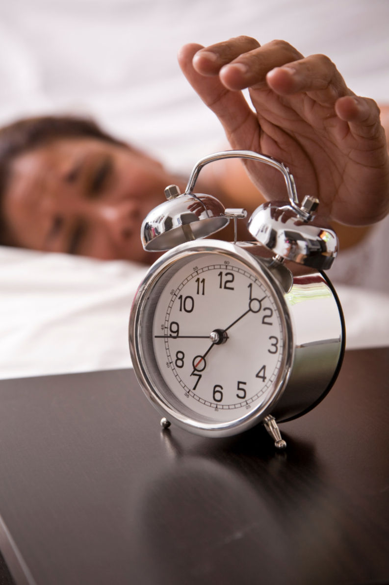 Person asleep beside an alarm clock, illustrating fatigue and disrupted sleep from nighttime mouth breathing.
