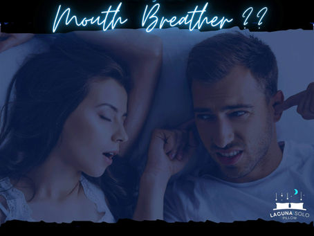 A dark bedroom where a man and woman are in bed.  The woman is snoring, fast asleep and the man is awake, annoyed and plugging his ears; just looking at her.