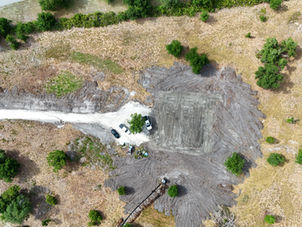 Aerial view of our homesite after site clearing and grading, showing the newly created house pad surrounded by the property.