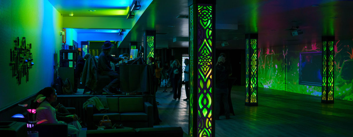 Lounge-style event space with green lighting, seating area, and illuminated columns designed for social gatherings and private events.