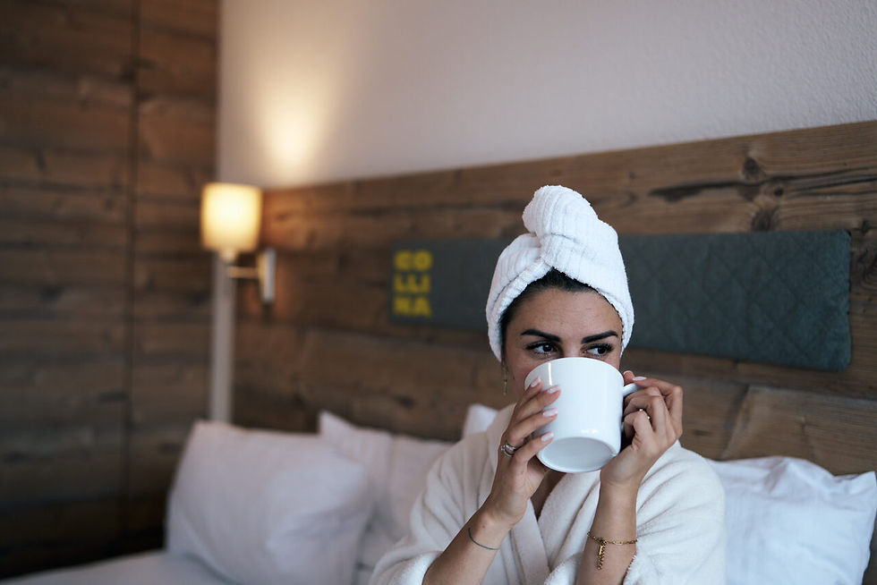 Woman in a bathrobe with a coffee cup in bed, chilling at Crew Flat Nauders, © karinpasterer.com