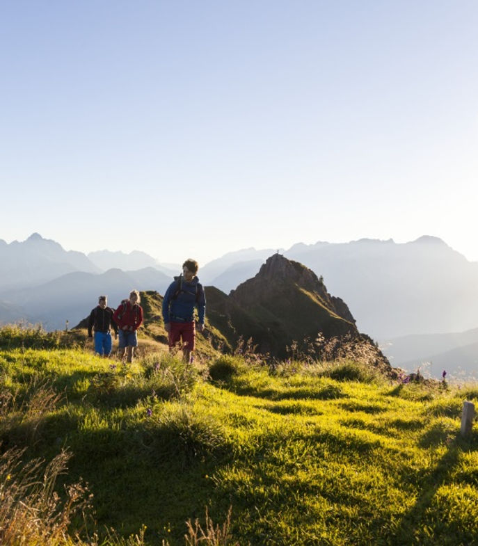 Wanderer auf Berggipfel bei Sonnenaufgang