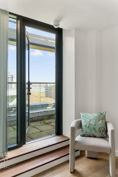 Chair with cushion by open balcony door.