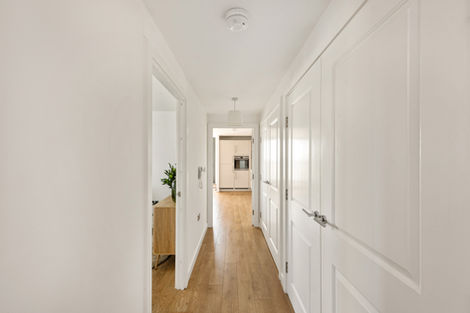 Bright hallway with wooden floor and white doors.