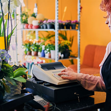 redhead female flower seller using cash register market shop