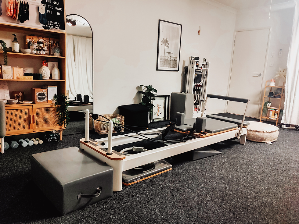 A bright, sunlit Pilates studio featuring a wooden reformer and a trapeze table, showcasing the clean and inviting environment at Zone Out Pilates.