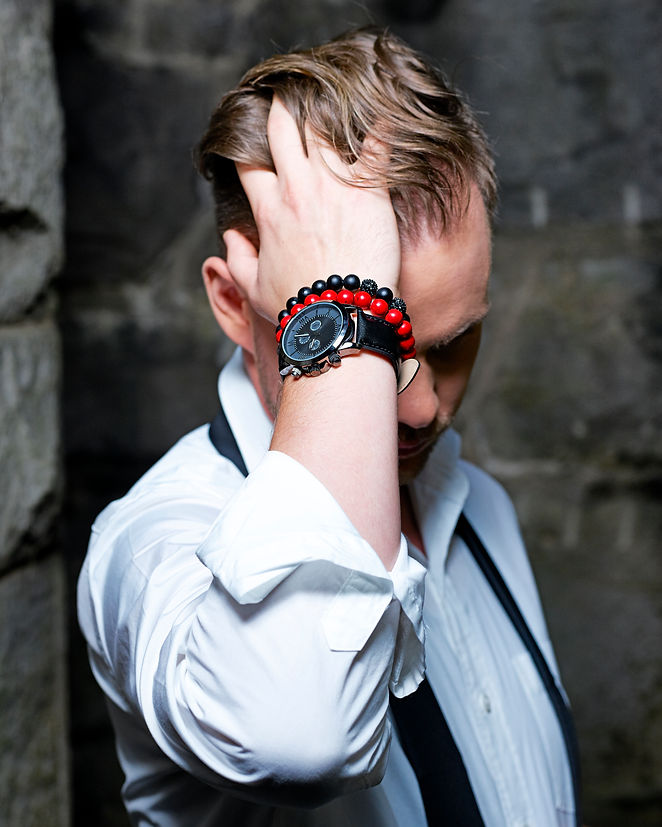 picture of a man wearing a black bracelet and a red bracelet with a black watch in a white shirt
