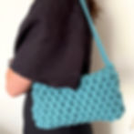 person wearing teal blue small shoulder bag with short strap