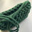 Thumbnail: close up of strap and top of dark green cotton cord knotted shoulder bag