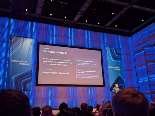 Main stage of Tokenomicon + FinOps X Amsterdam 2026 at the Muziekgebouw, with the slide 'The illusion of cheap AI' on screen