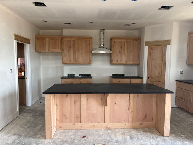 New kitchen with wooden cabinets, island, and appliances in construction phase.