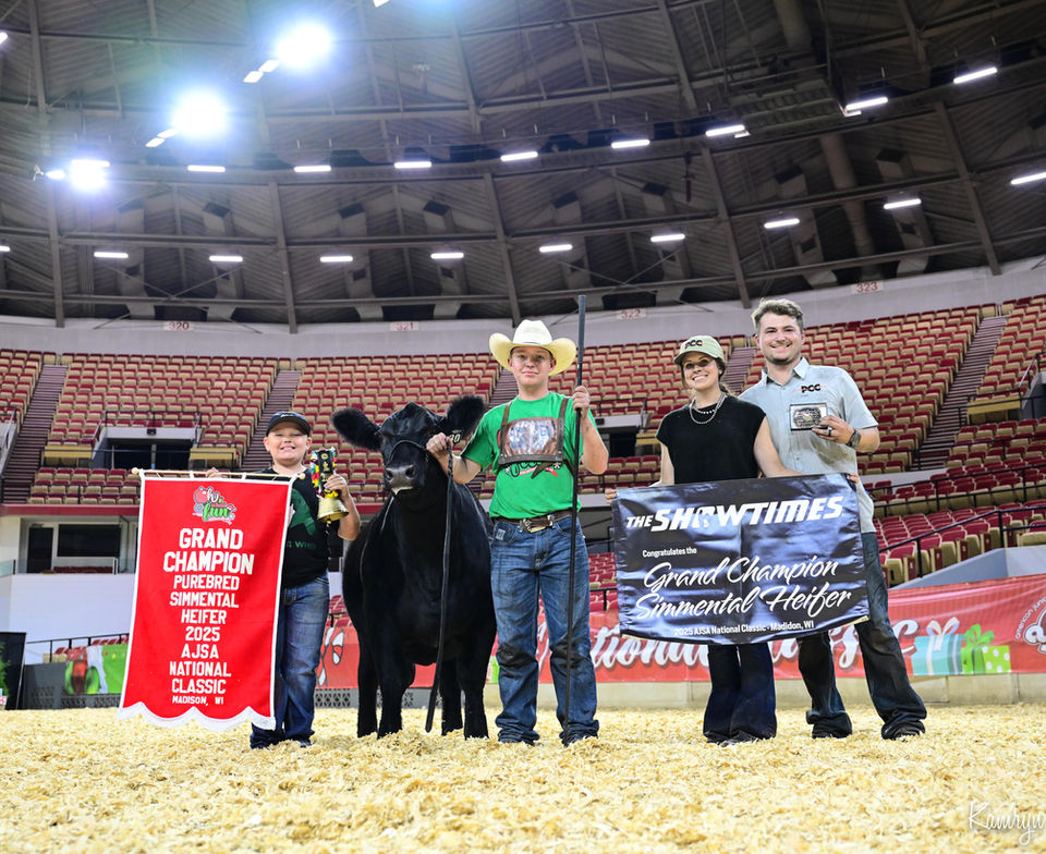 Four people and Grand Champion Heifer with awards at a show.