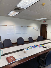 Conference room with table, chairs, markers, and whiteboards for a meeting.