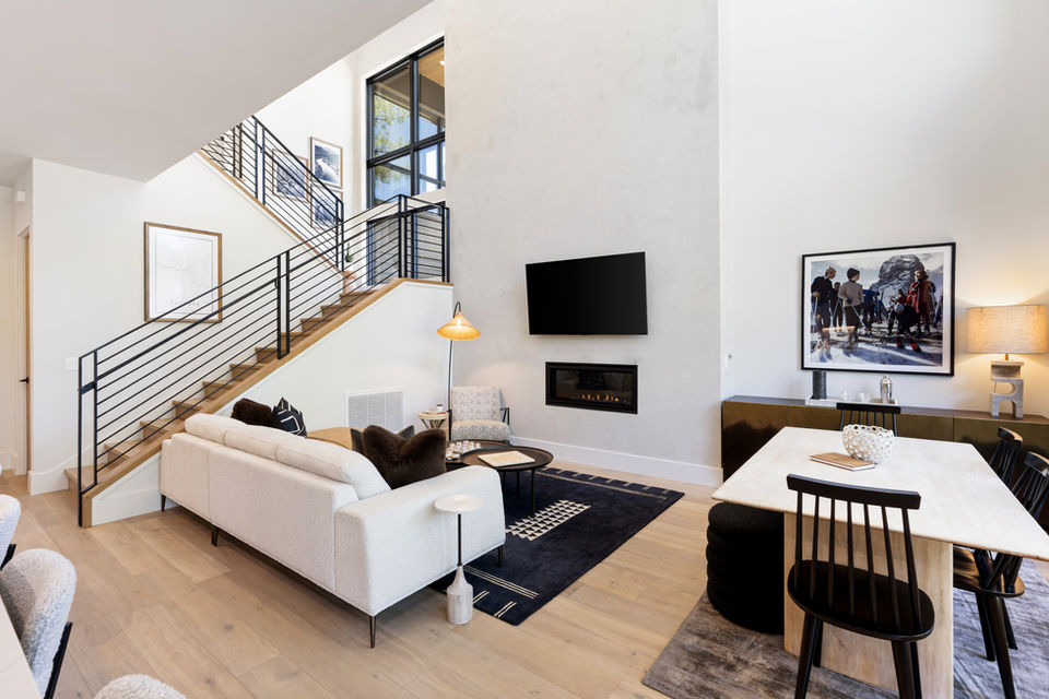 Bright and airy great room with soaring ceilings, abundant natural light, cozy gas fireplace, and a 65” smart TV for ultimate comfort and entertainment.