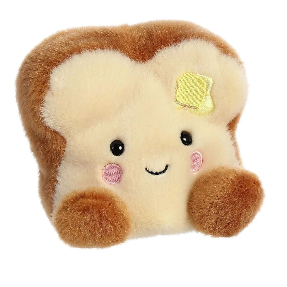 Front view Palm Pals 11cm Buttery Toast plush toy. Features light body and back with brown crust, pink cheeks and yellow doto