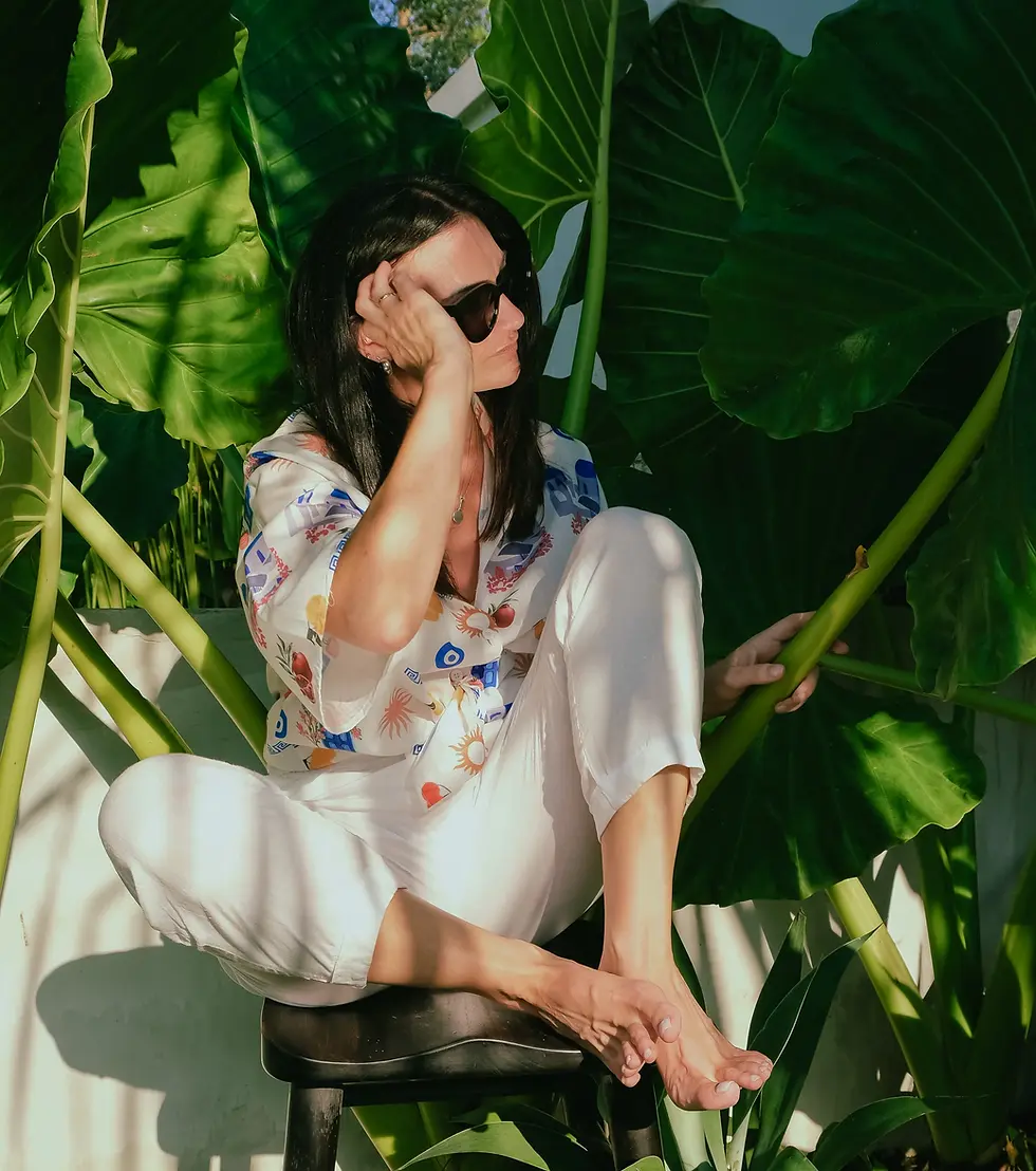 Woman in sunglasses sitting among tropical plants.