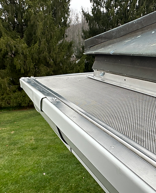 Close-up of premium stainless steel micro-mesh gutter guards installed by Shepherd & Sons on a white K-style seamless gutter in Baltimore County, Maryland. Fine mesh blocks pine needles, leaves, and debris while allowing maximum water flow.