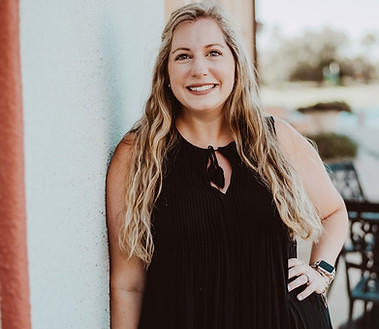 a caucasian woman smiling leaning against a wall