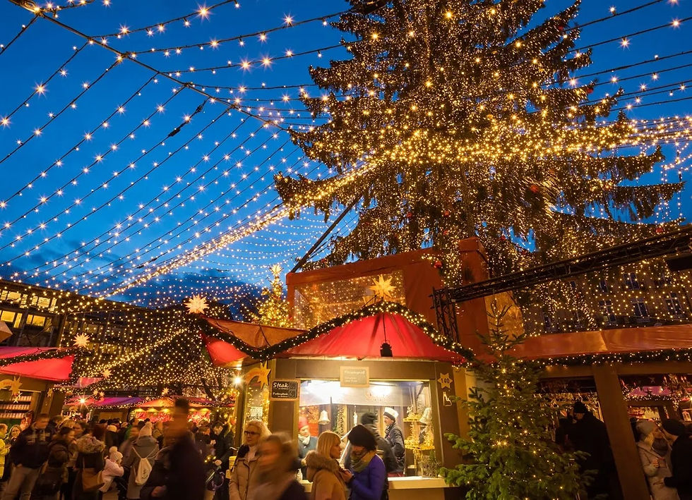 Christmas market at night with a giant lit tree and strings of lights over the stalls