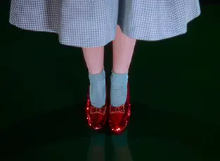 Sequined red shoes on the feet of a woman in a blue and white gingham dress