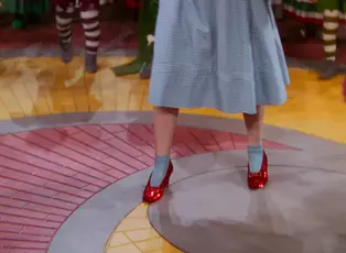 Sequined red shoes on the feet of a woman in a blue and white gingham dress