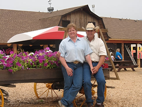 Couple posing by flower wagon in front of a barn