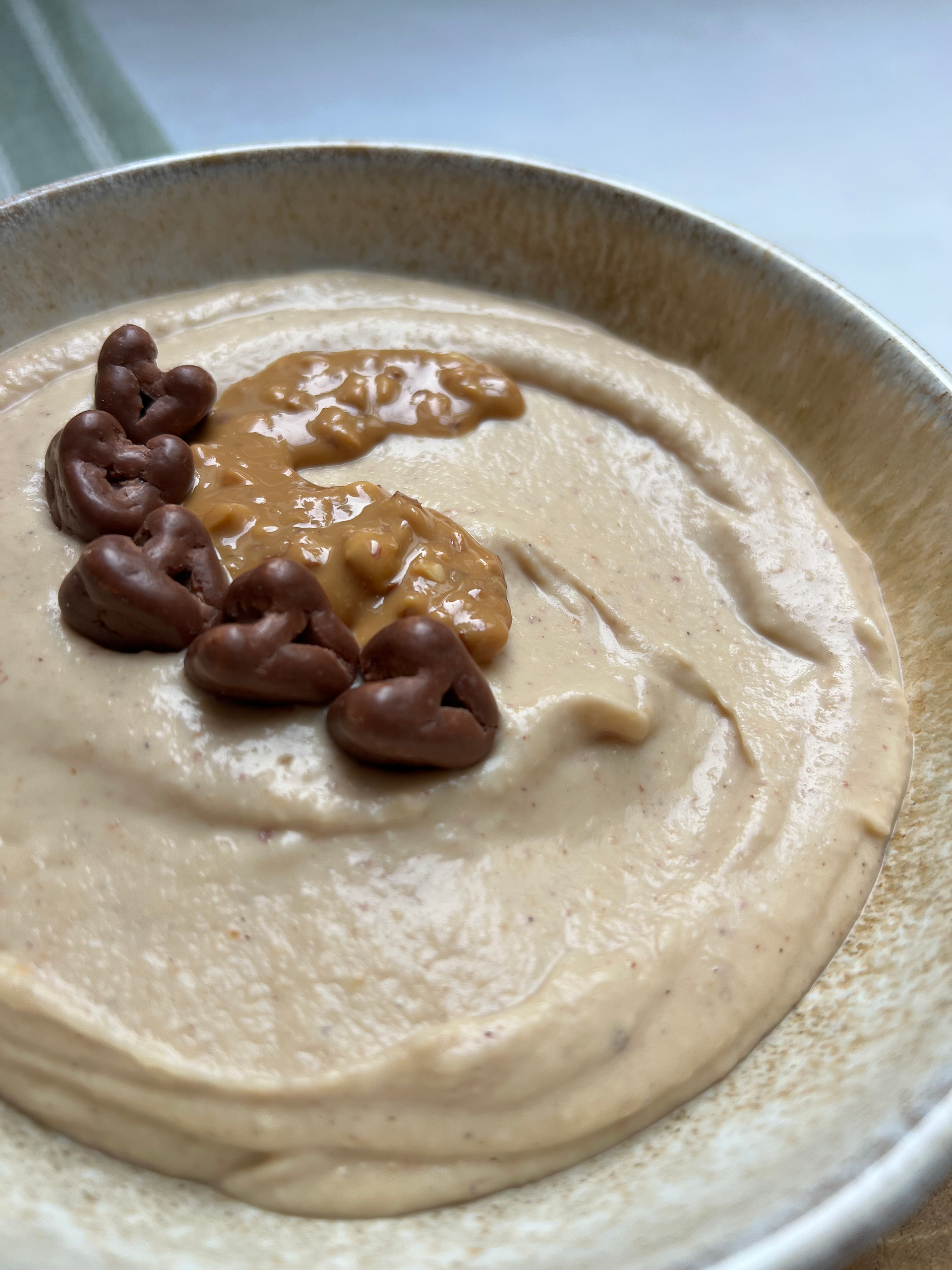 high protein cookie dough in einer hellen Schüssel auf einem Holzbrettchen, grün-weißes Geschirrtuch