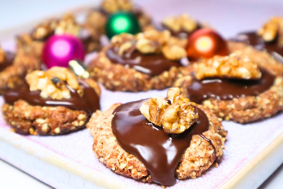 Zuckerfreie Dattel Mandel Cookies mit Zartbitterschokolade und Walnüssen verziert, dekoriert mit pinken und grünen Weihnachtskugeln  auf einem rosa Teller