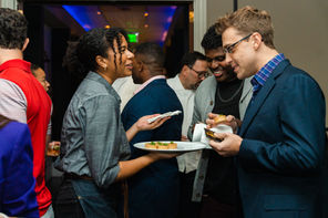 Guests exchanging introductions at a rooftop mixer with city views
