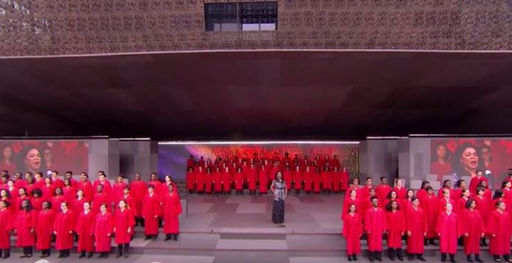A choir of around 80 teenagers in bright red robes performs with Denyce Graves in front of the Smithsonian's National Museum of African American History and Culture. 