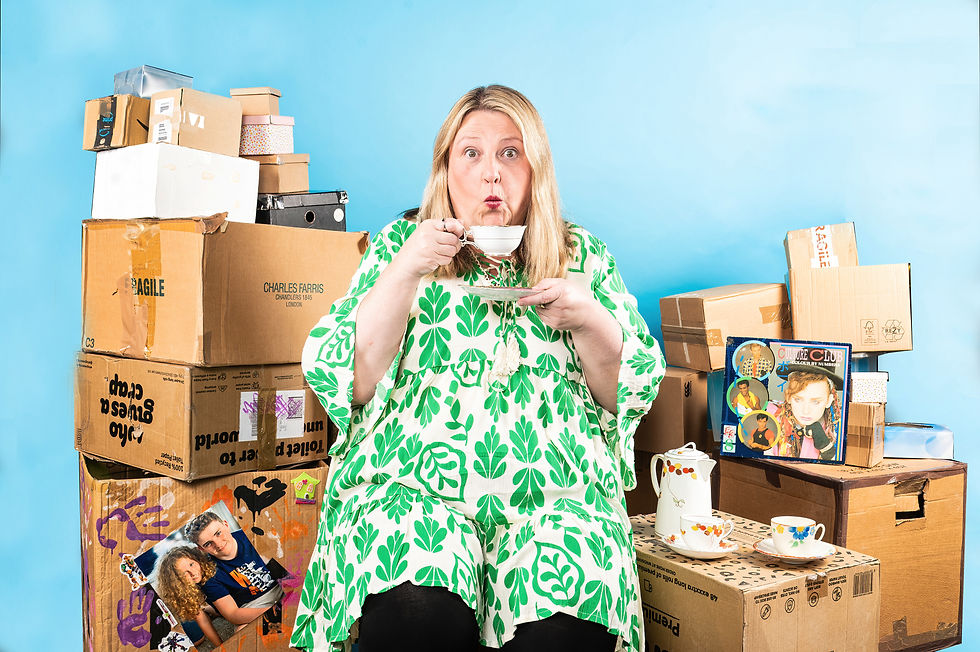 Joann Condon sipping tea among cardboard boxes and a Culture Club record.