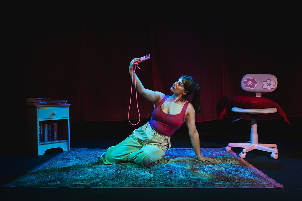 Woman on a rug takes a selfie with a pink phone in a neon-lit room, beside a small shelf and a flower-back chair.