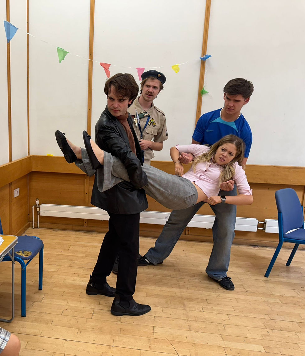 The cast in mid-chaos as one character lifts another in the middle of a confrontation