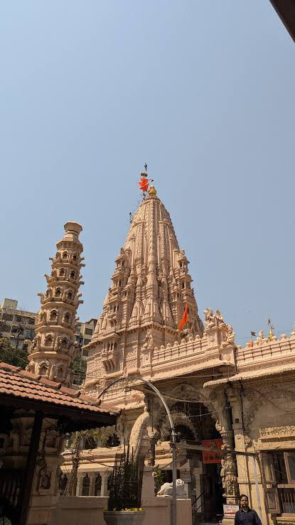 Tall stone shikhara of Babulnath Temple with carved details and saffron flags on top