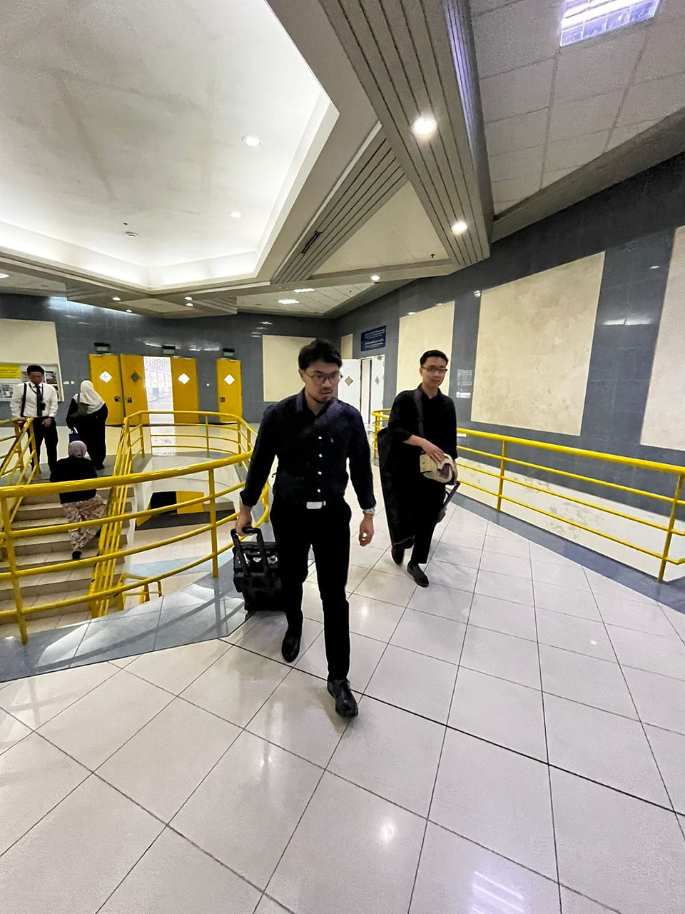 2 men carrying camera equipment taking large strides