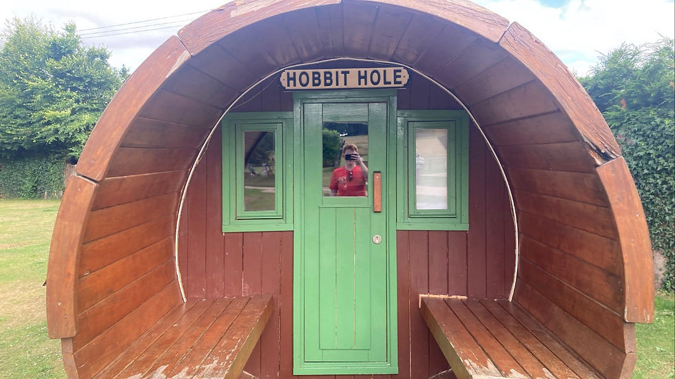 A round hut with a green door with hobbit hole written on it