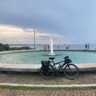 A bicycle in front of a blue fountain by the sea