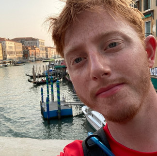 A ginger man in front of a venetian canal