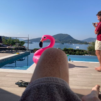 A pool with a pink flamingo float in front of the sea