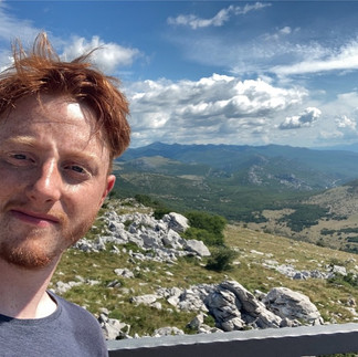 Me in front of a rocky Croatian vista with wooded hills behind