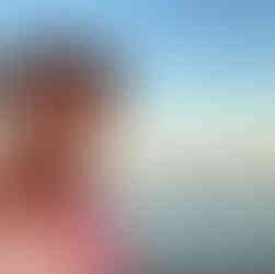 Me smiling in front of a pink sunset over the sea