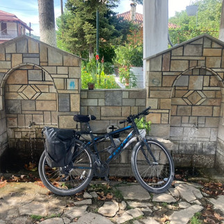 A battered bicycle leaning against a small public fountain