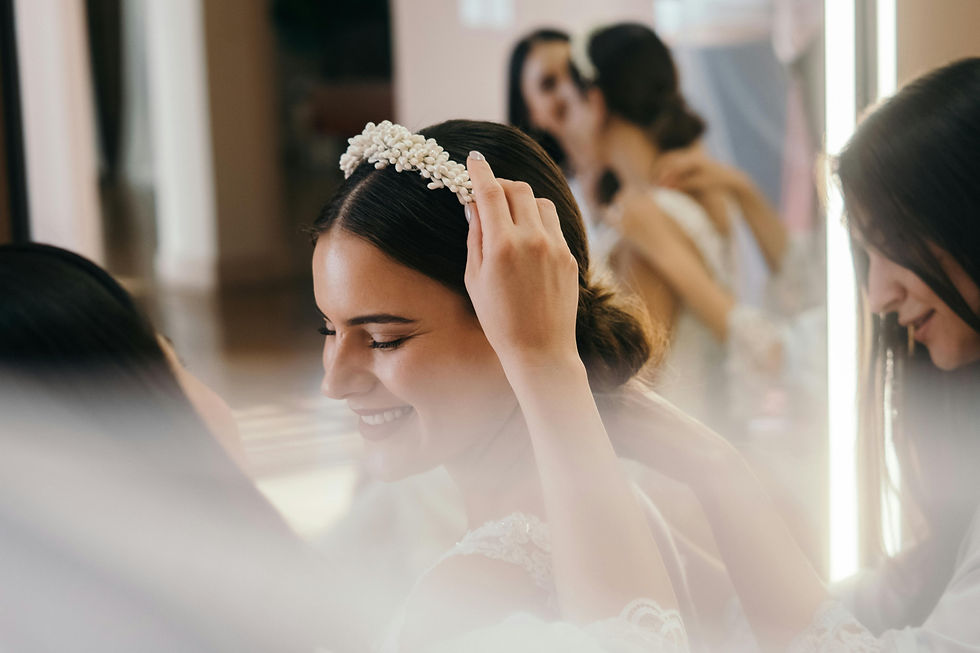 The bride exudes joy as her makeup artist helps her prepare for her big day, carefully adjusting her elegant headpiece.