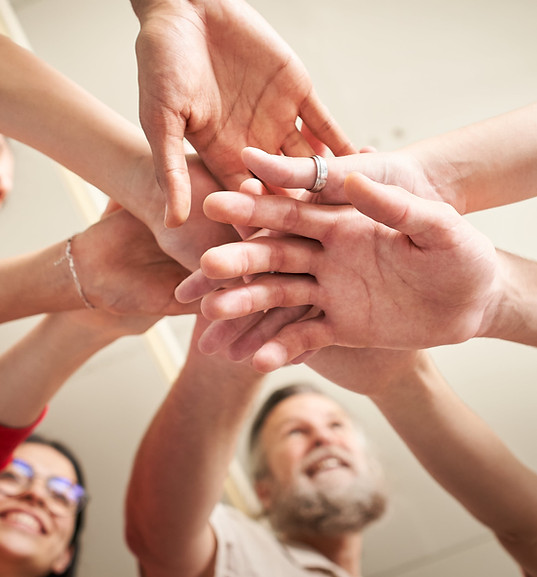 Group of people joining hands in a team-building unity gesture