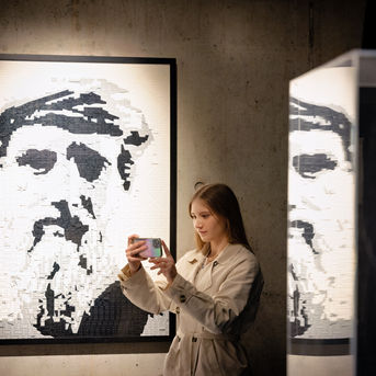 Femme photographiant un portrait d'homme barbu noir et blanc.